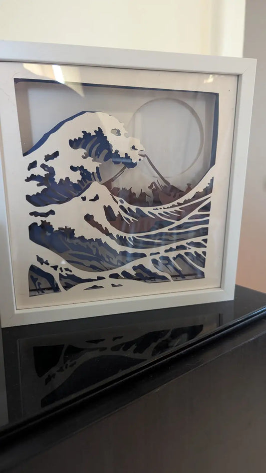 Lightbox artisanale en papier représentant La Grande Vague de Kanagawa, découpe multilayer dans un cadre blanc