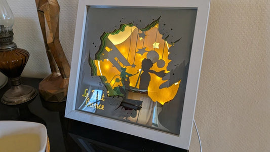 Lightbox Le Petit Prince vue de côté sur meuble, profondeur shadow box visible, câble USB apparent