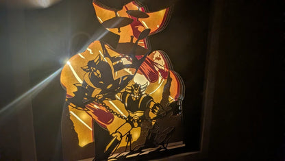 Cadre lumineux en papier découpé représentant le robot Goldorak, style rétro-gaming.