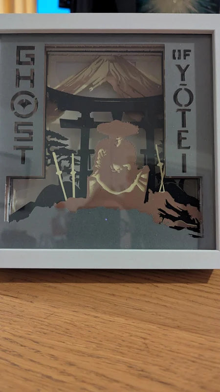 Lightbox Ghost of Yotei éteinte montrant les couches de papier, le samouraï et le mont Yotei