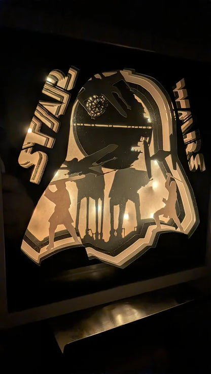 Détail lumineux de la lightbox Star Wars avec silhouettes de soldats et AT-AT, éclairage chaud et découpe papier multicouche