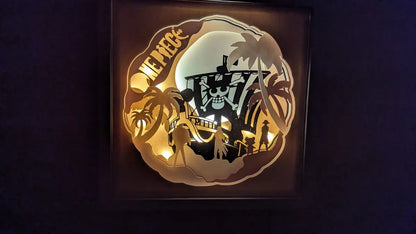 Lightbox One Piece découpée en couches de papier avec le Thousand Sunny et les personnages Luffy, Zoro et Chopper – scène lumineuse artisanale