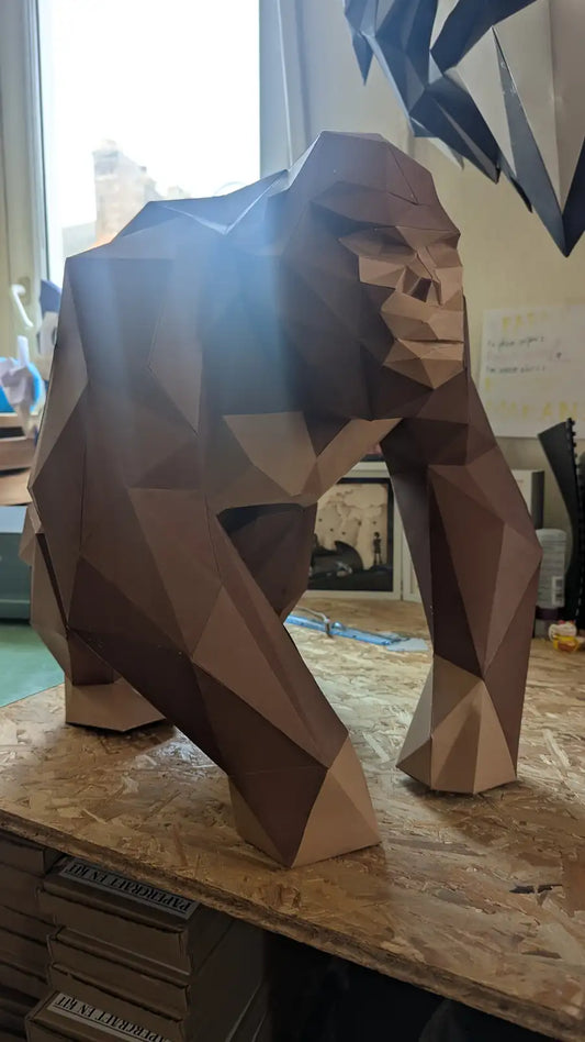 Papercraft gorille XL en papier marron vu en contre-plongée, mettant en avant la puissance et les détails géométriques du modèle