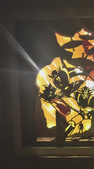 Séquence vidéo montrant l'effet de profondeur 3D créé par les différentes couches de papier découpé dans une lightbox Goldorak allumée, avec un zoom sur le robot et une petite silhouette.